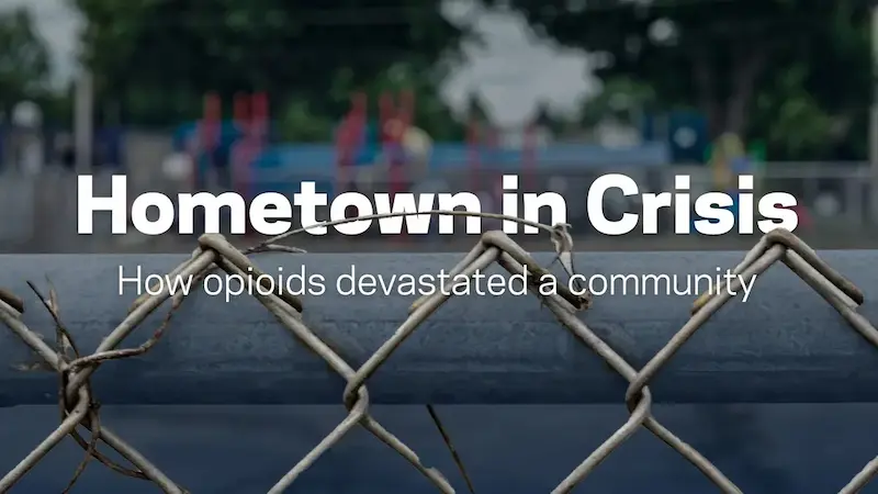 A blurred background of a playground with a chain-link fence in the foreground, and white text that reads “Hometown in Crisis: How opioids devastated a community.”